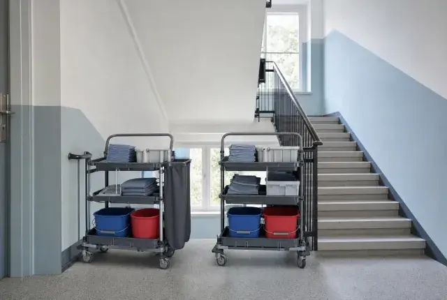 Zwei gleich bestückte Reinigungswagen im Treppenhaus Zwei identisch bestückte Reinigungswagen nebeneinander in einem hellen Treppenhaus mit blauer Wandzone
